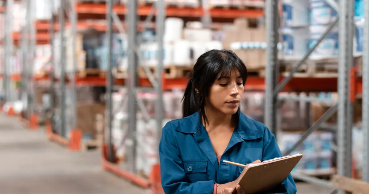 Professional woman holding a tablet in a modern warehouse, representing inventory management and ERP solutions