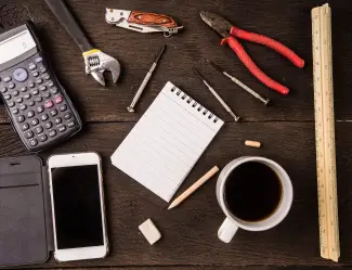 Tools, a notebook, and a cup of coffee on a wooden table, symbolizing planning and preparation for a successful SAP Business One implementation.