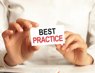 Hands holding a card with the words 'Best Practice,' representing effective strategies and methodologies in business operations.