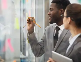 Two business professionals discussing strategies on a transparent board, showcasing collaboration at an ERP in Michigan.