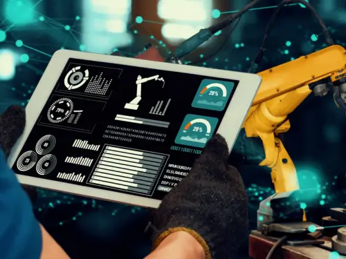 Tablet showcasing manufacturing software for small businesses with a robotic arm in a factory setting.