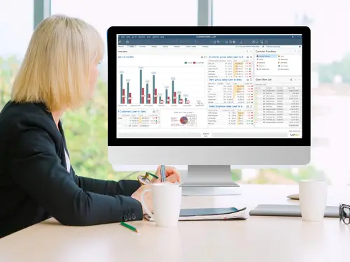 Businesswoman analyzing charts and data on a desktop screen to select the best manufacturing software solution.