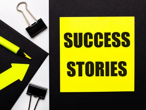 Yellow sticky note with 'Success Stories' written on it, surrounded by office supplies and an upward arrow