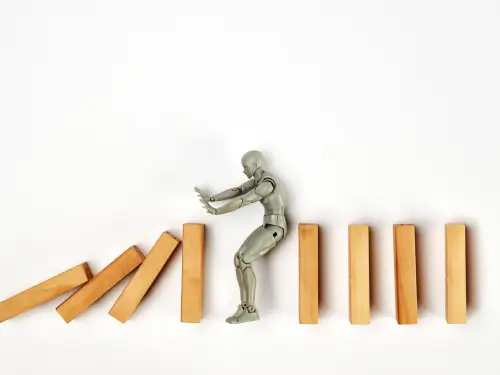 Figure stopping falling wooden blocks, symbolizing overcoming challenges in manufacturing software for small businesses