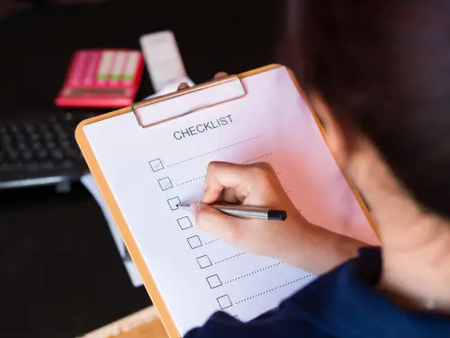 Person filling out an ERP checklist on a clipboard in a professional workspace